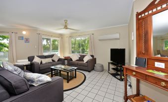 a spacious living room with a couch , chairs , and a tv . also a dining table in the room at Marina Terraces Port Douglas