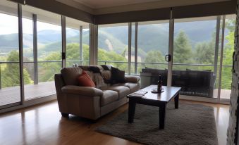 a spacious living room with a couch , coffee table , and large windows overlooking a scenic view at Abby's Cottages
