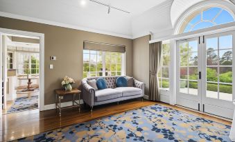 a cozy living room with a large couch and a rug on the floor , creating a warm and inviting atmosphere at Parklands Country Gardens & Lodges Blue Mountains