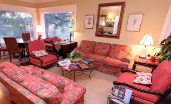 a living room with a red couch and chairs , a coffee table , and two lamps at Arroyo Vista Inn