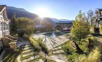 a large , modern house with a swimming pool and lush greenery surrounding it , set against the backdrop of mountains and a sunny day at The Himalayan
