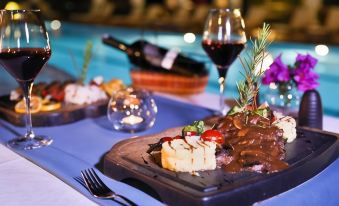 a dining table with a variety of food and drinks , including a plate of meat and wine , a glass of wine , and a bottle of at Happy Hotel Kalkan