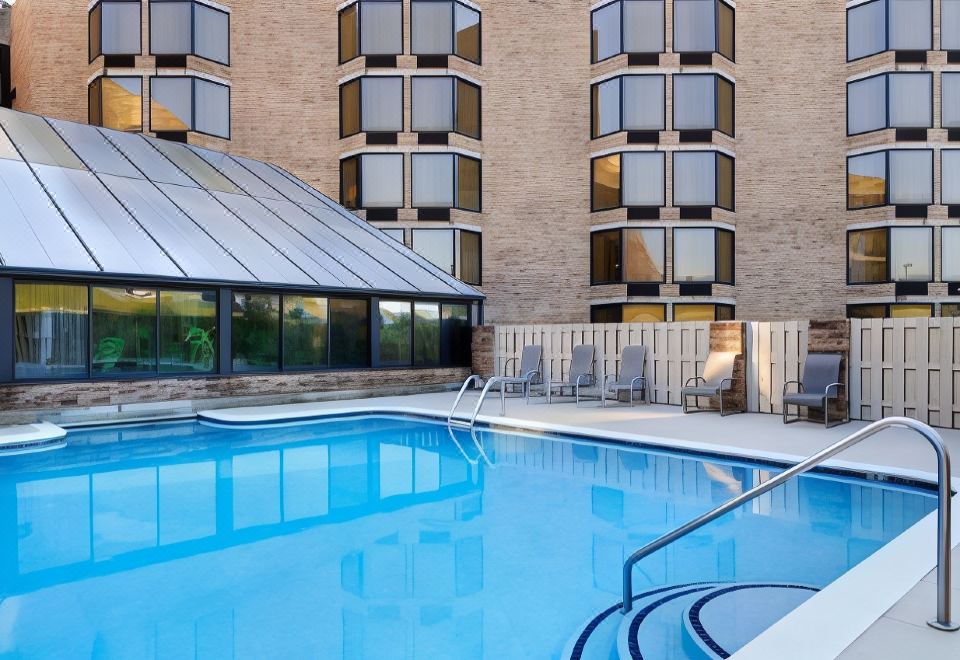 a large outdoor swimming pool surrounded by multiple buildings , with people enjoying their time in the pool at DoubleTree by Hilton Hotel Murfreesboro