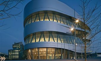 a modern building with a curved facade and large windows is lit up at night at Stuttgart Marriott Hotel Sindelfingen