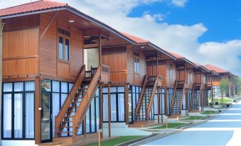 a row of wooden houses with red roofs and stairs leading up to them , under a blue sky at Jsi Resort