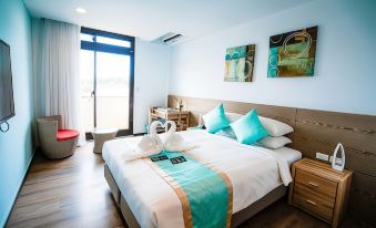 a large bed with a white and blue comforter is in a room with wooden floors at Palau Hotel