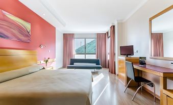 a modern hotel room with a red accent wall , large windows offering views of the outdoors , and a comfortable bed at Hotel Maya Alicante
