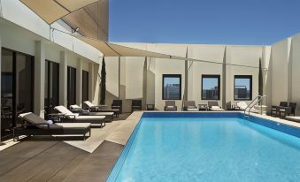 a rooftop pool surrounded by lounge chairs , with several people enjoying their time in the pool at Stamford Plaza Adelaide