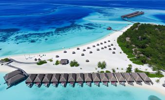 aerial view of a tropical beach with a row of beach huts and clear blue water at Constance Moofushi