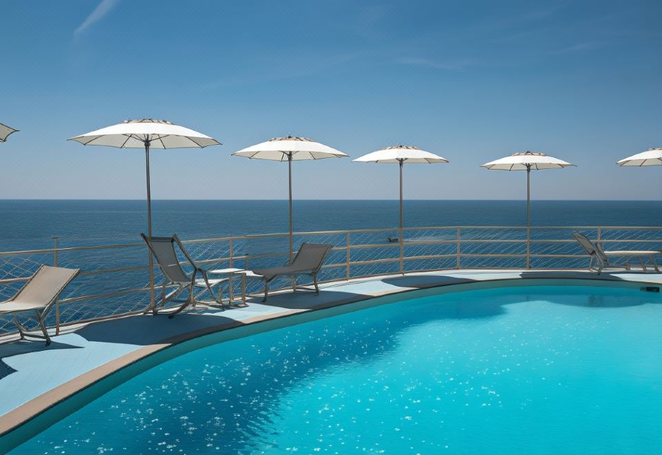 a swimming pool with umbrellas and lounge chairs , surrounded by the ocean and a clear blue sky at Hotel Miramalfi