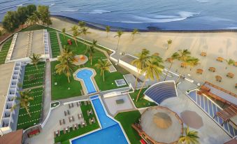 a bird 's eye view of a resort with a pool , grassy area , and palm trees near the beach at Sunset Beach Hotel