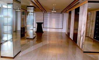 a long hallway with white walls and polished wooden floors , featuring a black vase in the center at Hotel Apaar