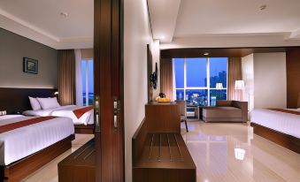 a modern hotel room with a large window offering a view of the city at night , a bed , couch , and kitchenette at ASTON Imperial Bekasi Hotel & Conference Center