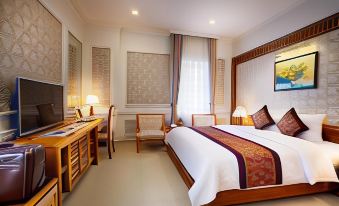 a large bed with a white and maroon blanket is in the middle of a room at Riverside Hotel Quang Binh
