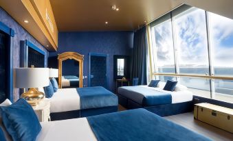 a modern hotel room with blue and white bedding , a large window , and wooden furniture at Arthouse Hotel
