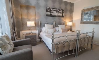 a modern bedroom with a silver bed , gray walls , and two lamps on either side of the bed at Carmel Apartments