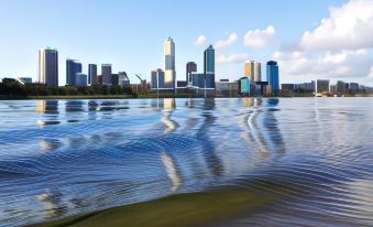 a city skyline reflected in a body of water , with ripples on the water and trees in the background at Broadwater Resort Como