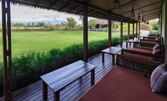 a wooden deck overlooking a grassy field , with several benches placed on the deck for patrons to sit and enjoy the view at Azalea Village