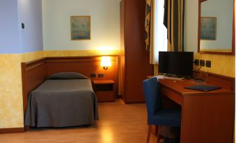 a hotel room with a bed , desk , and chair , along with a tv and other amenities at Hotel Majestic