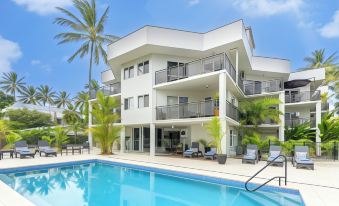 a large , modern apartment building with a swimming pool in the backyard , surrounded by palm trees at Marina Terraces Port Douglas