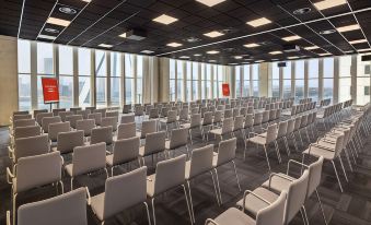 an empty conference room with rows of white chairs and large windows , providing a view of the city at Nhow Rotterdam