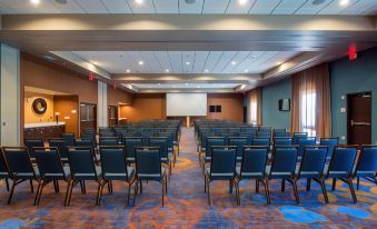 a large conference room with rows of blue chairs arranged in front of a projector screen at Courtyard LaGrange