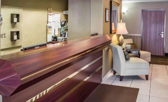 a hotel lobby with a wooden reception desk and a chair , as well as a doorway leading to another room at Wingate by Wyndham Clearfield