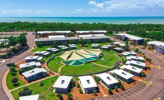 an aerial view of a large circular facility with several buildings and a beach in the background at Club Tropical Resort Darwin