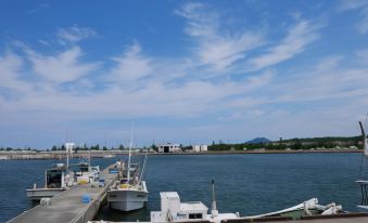 a dock with several boats docked , including a large white boat , and the sky above at Yamadaya