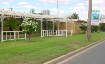 a grassy field with a white fence and a gazebo in the background , surrounded by trees at Ardeanal Motel