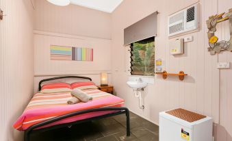 a bedroom with a bed , nightstand , and air conditioning unit , along with a small air conditioner and light switch at Dreamtime Travellers Rest