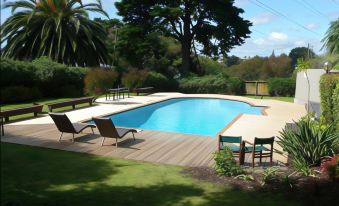 a large backyard with a swimming pool surrounded by lounge chairs and a wooden deck at Waipuna Hotel & Conference Centre