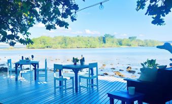 a wooden deck overlooking a body of water , with tables and chairs set up for outdoor dining at Turtle Bay Lodge