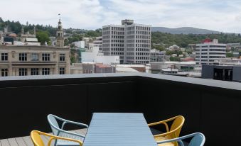 a blue table and yellow chairs are set up on a rooftop patio overlooking a city at The Chamberson