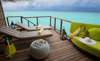 a wooden deck overlooking the ocean , with lounge chairs and a table placed on it at Outrigger Maldives Maafushivaru Resort