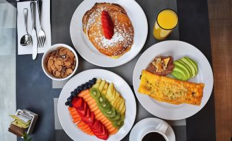 a table is set with plates of food , including a pancake and fruit , as well as a cup of coffee at Courtyard Ciudad Juarez