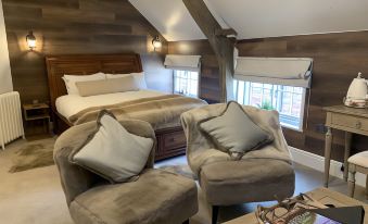 a bedroom with a bed , two chairs , and a window , all set against wooden walls at The Boot Inn