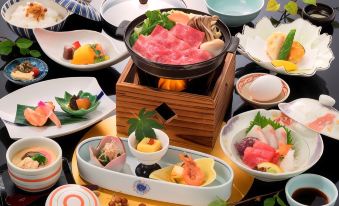 a dining table with a variety of food items , including sushi , meat , and other dishes at Hotel Verde