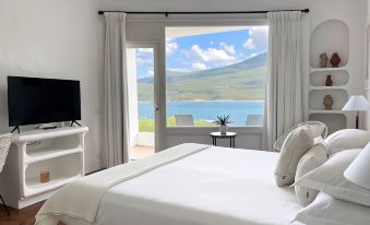 a bedroom with a large window overlooking a beautiful view of the ocean , and a bed with white linens at A’mare Corsica Seaside Small Resort