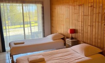 a room with two beds , one on the left side and another on the right side of the room at Logis le Chalet