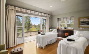 a room with two massage tables , one on the left and one on the right , and a window overlooking a grassy field at Parklands Country Gardens & Lodges Blue Mountains