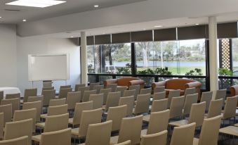 an empty conference room with rows of chairs and a large window overlooking a grassy field at Berri Hotel