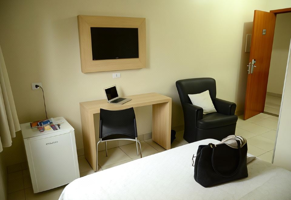 a hotel room with a desk , chair , and laptop , as well as a bed and other furnishings at Hotel Capital