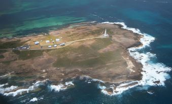 aerial view of a small island with a lighthouse on it , surrounded by blue water and sandy beaches at Augusta's Georgiana Molloy Motel