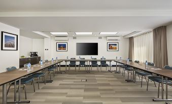 a conference room with a long table , chairs , and a large screen on the wall at Quest Kings Park