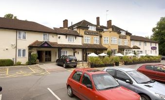 "a red car is parked in front of a large building with the sign "" the caverne "" on it" at Premier Inn Bagshot