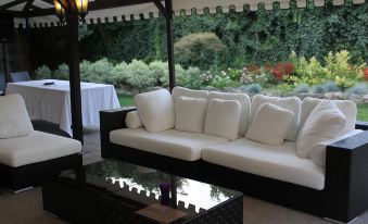 a white couch and a black coffee table are placed in front of a glass table with a view of the garden at Blue Dream Hotel
