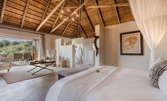 a bedroom with a large bed and white linens is shown with a wooden ceiling at Bukela Game Lodge - Amakhala Game Reserve