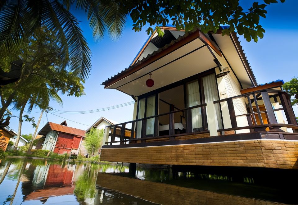 a wooden house with a balcony overlooks a flooded area surrounded by trees and water at Lampam Resort