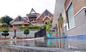 a large house with a pool in front of it , surrounded by trees and bushes at Khas Parapat
